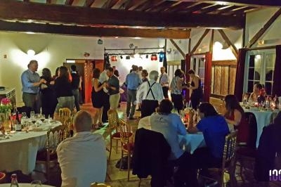 Des invités dansent et dînent dans une salle de réception décorée avec des tables dressées et un éclairage chaleureux.