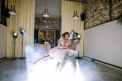 Un couple danse dans une salle éclairée, entouré de fumée et de lumières de scène.