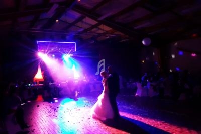 Un couple danse sous des lumières colorées dans une salle sombre lors d'une réception.