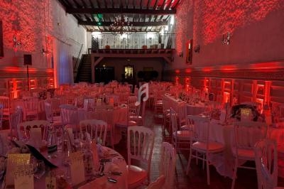Salle de réception décorée avec des tables rondes, nappes blanches et éclairage rouge créant une ambiance chaleureuse.