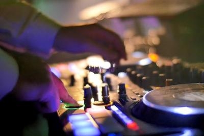 Mains ajustant des commandes sur une table de mixage lumineuse dans un environnement faiblement éclairé.