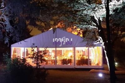 Tente éclairée la nuit dans un jardin, avec des arbres autour et des lumières intérieures visibles à travers les parois.