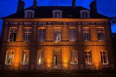 Façade d'un bâtiment en briques éclairée par des lumières jaunes, photographiée de nuit.