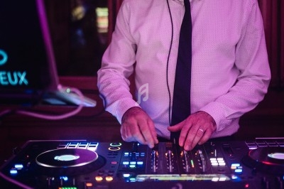 Un DJ mixe de la musique sur une table de mixage dans une ambiance lumineuse violette.