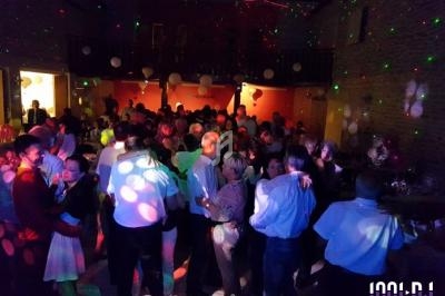 Groupe de personnes dans une salle éclairée par des lumières colorées, lors d'une soirée dansante.
