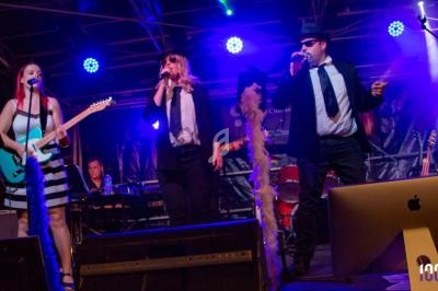 Un groupe de musiciens et chanteurs se produit sur scène sous des éclairages colorés.