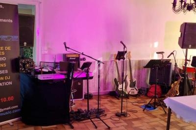 Équipement musical installé dans une salle, comprenant instruments, micros, amplis et une affiche promotionnelle.