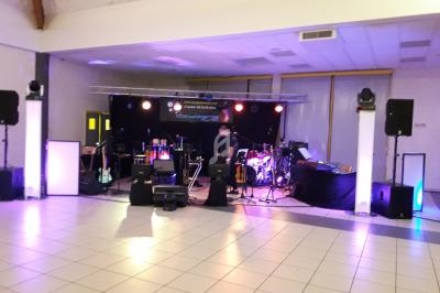 Scène de concert en intérieur avec instruments, éclairages colorés et matériel de sonorisation installé.