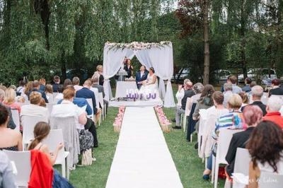 Cérémonie de mariage en plein air avec des invités assis, une allée centrale et un couple devant un autel décoré.