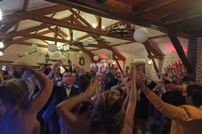Groupe de personnes dans une salle en bois, levant les bras lors d'une fête ou d'une célébration.