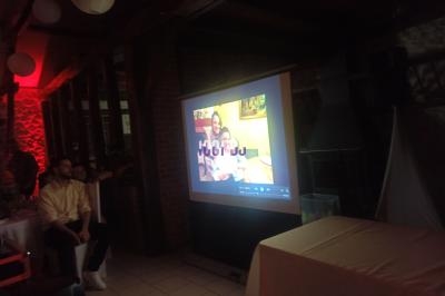 Projection d'une photo de famille sur un écran dans une salle éclairée par des lumières tamisées rouges.
