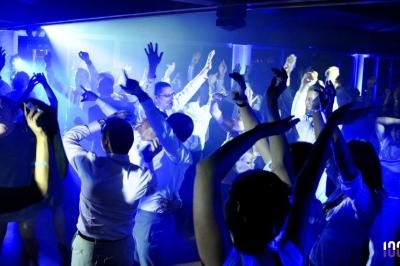 Personnes dansant sous des lumières bleues dans une ambiance festive en soirée.