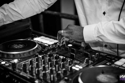 Un DJ ajuste les commandes d'une table de mixage dans un environnement sombre.