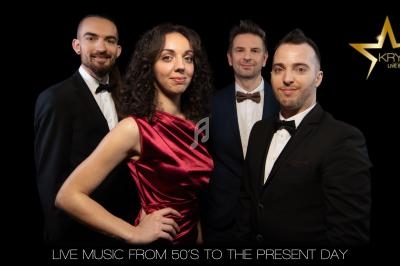 Quatre musiciens en tenue élégante posent devant un fond noir avec un logo en forme d'étoile dorée.