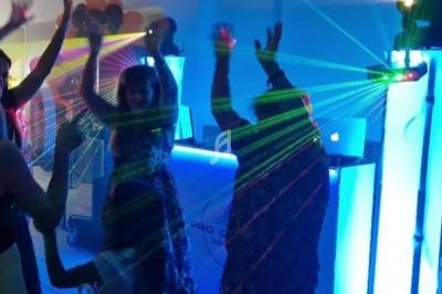 Personnes dansant sous des lumières colorées et des lasers dans une ambiance festive en intérieur.