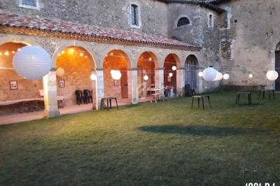 Cour extérieure d'un bâtiment ancien avec des arches, décorée de lanternes suspendues et de tables dispersées.