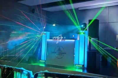 Jeu de lumières colorées et lasers projetés sur une scène avec une barrière décorée de toiles d'araignée.
