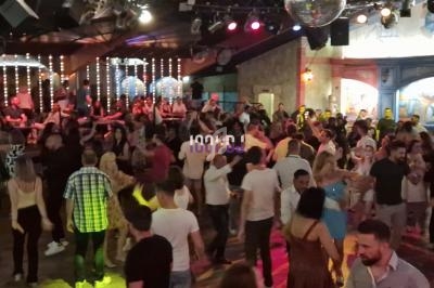 Personnes dansant dans une salle animée avec éclairages colorés et décorations lumineuses.