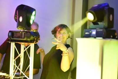 Femme souriante dans un environnement festif, éclairée par des projecteurs colorés.