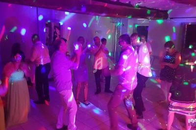 Des personnes dansent dans une salle éclairée par des lumières colorées lors d'une fête ou d'un événement.