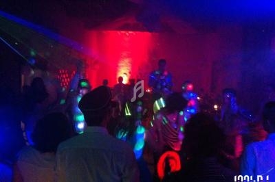 Personnes dansant dans une salle sombre éclairée par des lumières colorées et des effets lumineux.