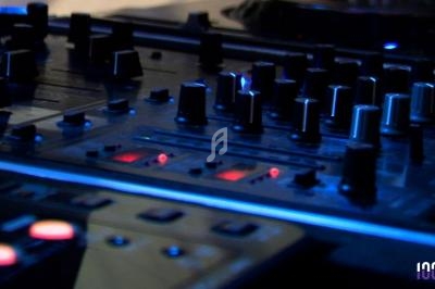 Table de mixage avec plusieurs boutons, curseurs et voyants lumineux dans un environnement faiblement éclairé.