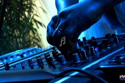 Main ajustant les commandes d'une table de mixage dans un environnement éclairé en bleu.