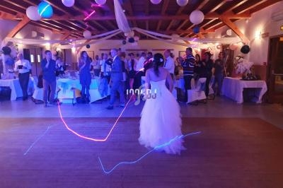 Une mariée en robe blanche danse dans une salle décorée avec des invités en arrière-plan.