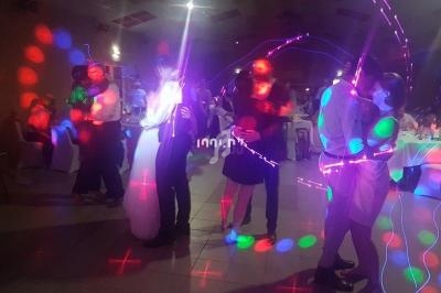 Des personnes dansent sous des lumières colorées dans une salle sombre lors d'un événement festif.