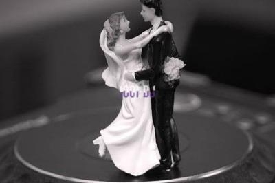 Figurines de mariés dansant, posées sur une surface circulaire en noir et blanc.