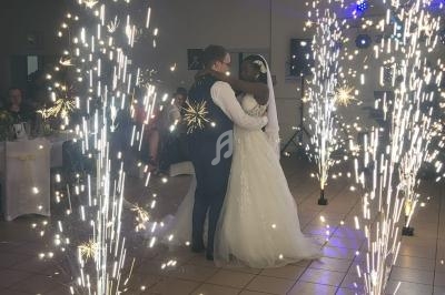 Un couple danse au centre d'une salle décorée, entouré de gerbes d'étincelles lumineuses.