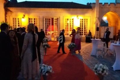 Personnes en tenue de soirée réunies sur un tapis rouge devant un bâtiment éclairé en soirée.