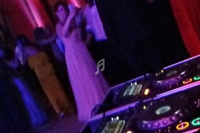 Des invités dansent dans une salle éclairée de lumières colorées, avec une table de mixage au premier plan.