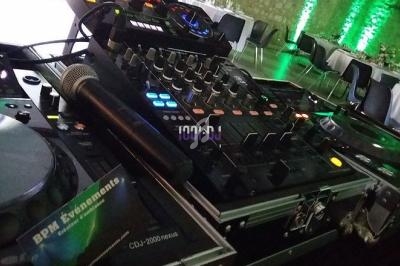 Table de mixage avec platines, micro et équipements audio installés dans une salle décorée de lumières vertes.