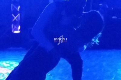 Un couple danse sous un éclairage bleu, l'homme inclinant la femme en arrière sur une piste sombre.