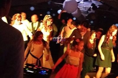 Des personnes dansent lors d'une fête, éclairées par des lumières colorées, avec une table de mixage au premier plan.