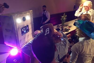 Des personnes utilisent un photobooth avec des accessoires festifs dans une ambiance lumineuse et conviviale.
