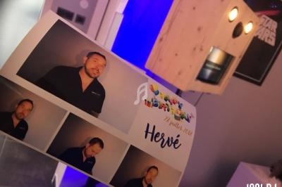 Photo d'une planche de tirages photo personnalisés avec un homme, prise devant une cabine photo en bois.