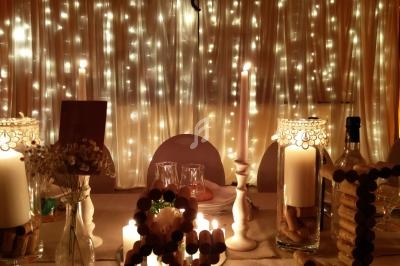 Table décorée avec des bougies, des guirlandes lumineuses et des éléments en liège dans une ambiance chaleureuse.