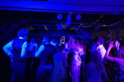 Des personnes dansent sous des lumières bleues dans une salle décorée de guirlandes lumineuses et de suspensions.