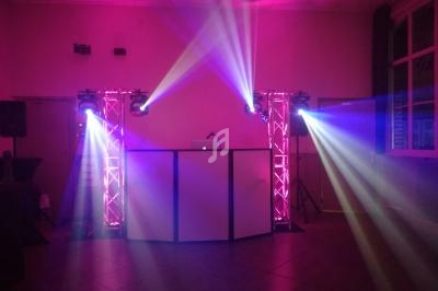 Installation de lumière de scène avec projecteurs colorés et console de DJ dans une salle sombre.