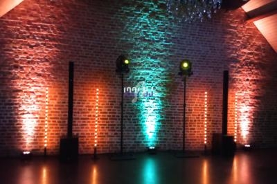 Éclairage coloré sur un mur de briques avec des projecteurs et des colonnes lumineuses dans une salle sombre.