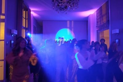 Groupe de personnes dans une salle éclairée par des lumières colorées, dansant et profitant d'une ambiance festive.