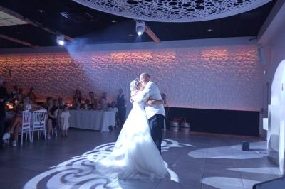 Un couple danse sous un éclairage tamisé dans une salle de réception décorée de motifs géométriques.
