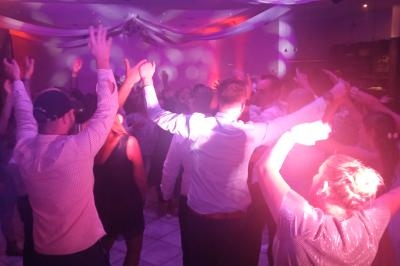 Groupe de personnes dansant sous des lumières colorées dans une ambiance festive en intérieur.