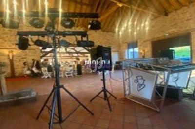 Équipement de sonorisation et éclairage installé dans une salle en pierre avec plafond en bois, tables dressées en arrière…