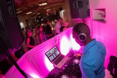 Un DJ mixe de la musique lors d'une soirée festive avec des invités dansant en arrière-plan.