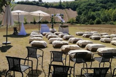 Chaises et bottes de paille disposées en extérieur pour une cérémonie, avec vue sur un paysage champêtre.