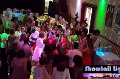 Groupe de personnes dansant et célébrant lors d'un événement festif dans une salle éclairée par des lumières colorées.