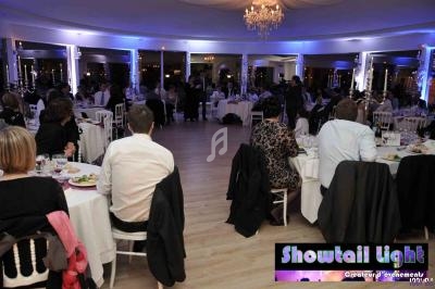 Salle de réception éclairée en bleu, avec des invités assis à des tables rondes lors d'un dîner événementiel.